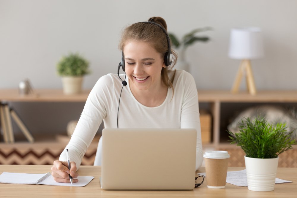 Remote Audio Jobs: smiling woman wear headset write notes