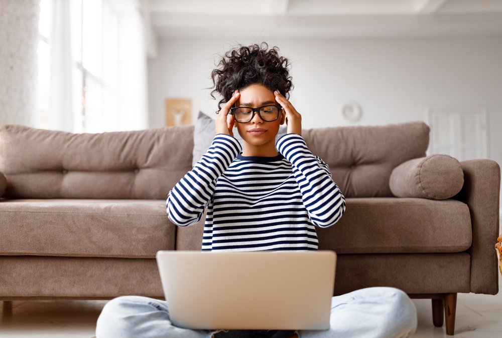 The Best and Worst Aspects of Remote Work: Picture of a tired ethnic woman with glasses touching head and closing eyes resting