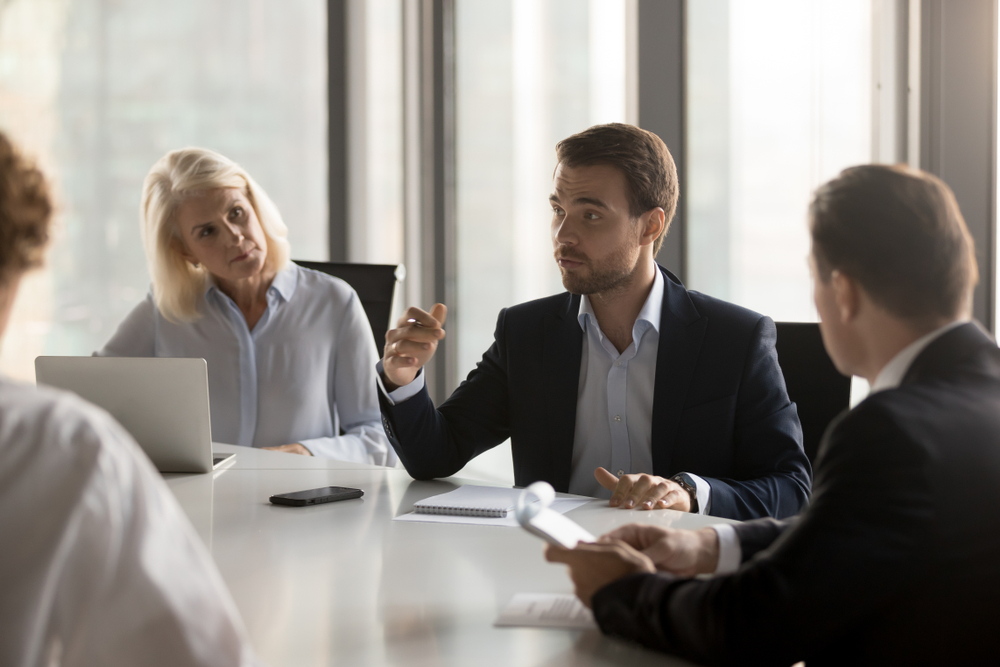 Top Paying Remote Jobs: Serious diverse colleagues brainstorm at conference table discuss project at meeting, focused businesspeople talk negotiating in office at briefing, business partners speak considering cooperation 