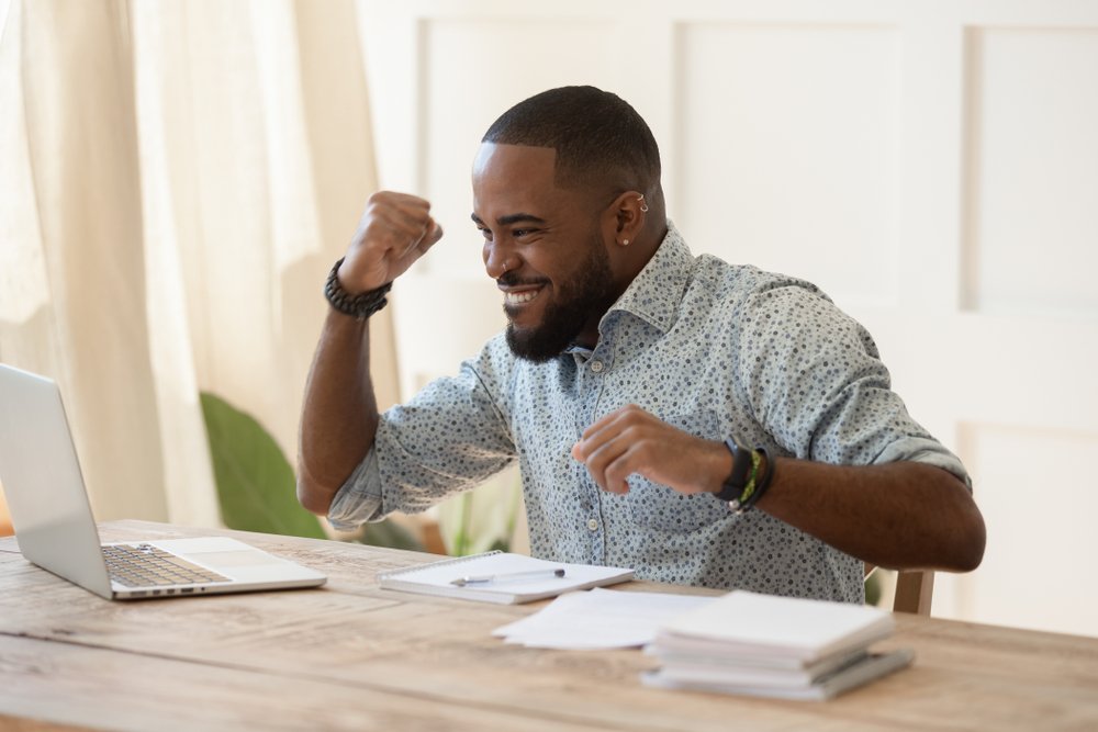 Best Remote Job Platforms: A picture of a black young man, celebrating getting a remote job