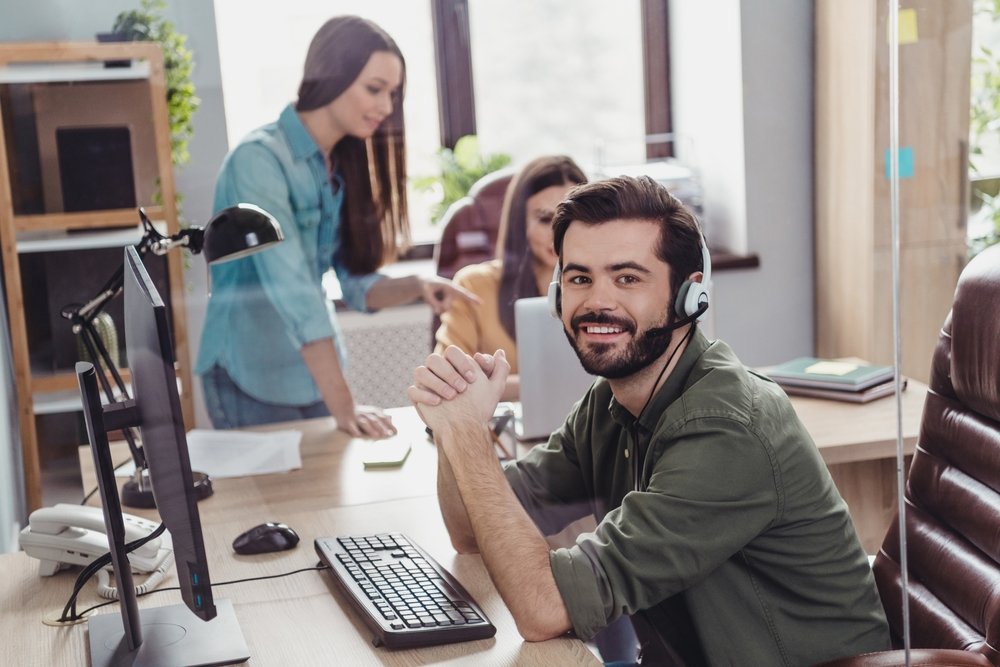 Remote Work Trends: Photo of three employee operator sitting chair communicate speak clients office building indoors.