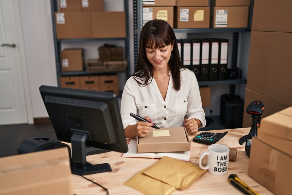 Work from Home Jobs for Women: A picture showing a young beautiful woman ecommerce business worker writing on package at office 