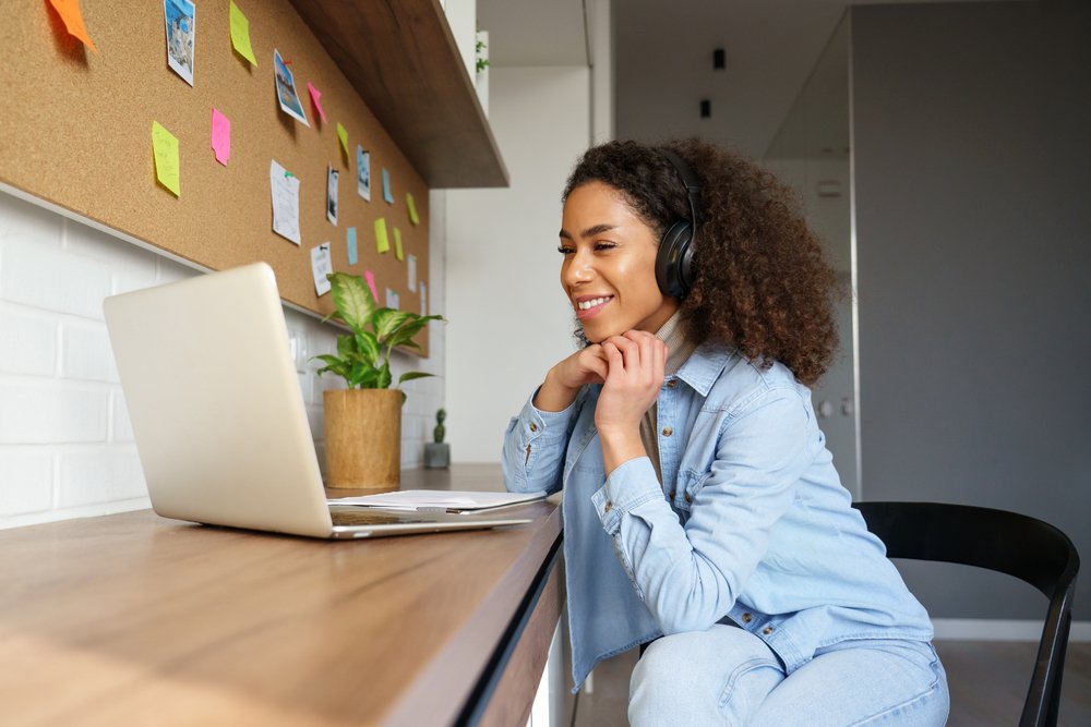 Remote Work Vs. In-Person Workshops: Picture of a lady learning online, and smiling at her laptop