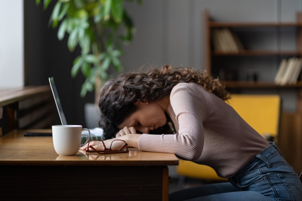 Remote Work Vs. Freelancing: Image of a young lady working from home on laptop looking worried, tired and overwhelmed. 