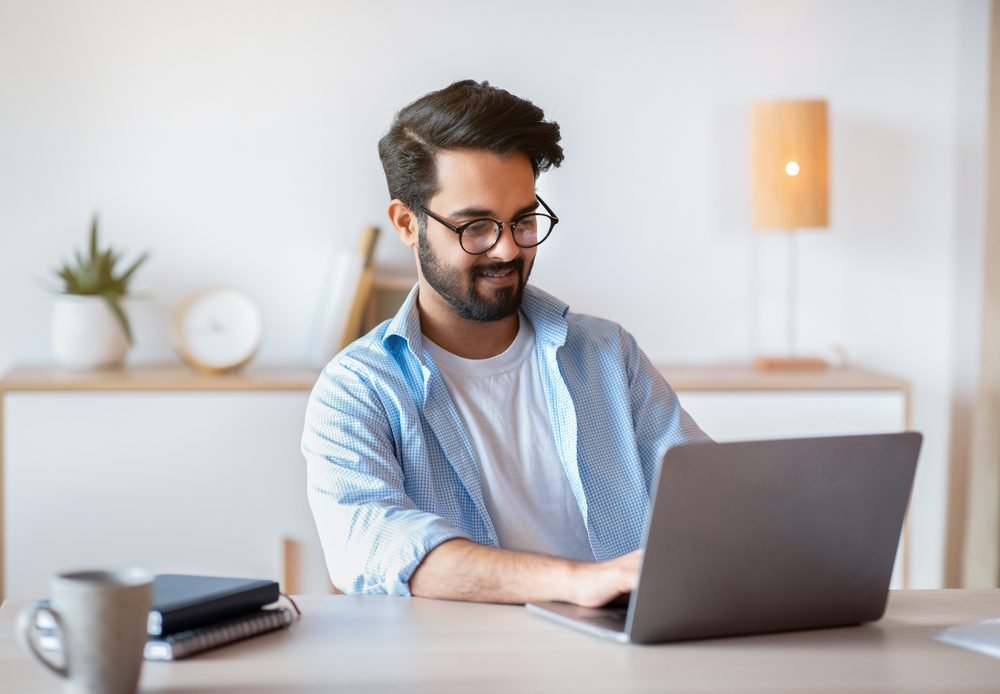 A man that was recruited for remote it jobs, sitting and working on his laptop from home