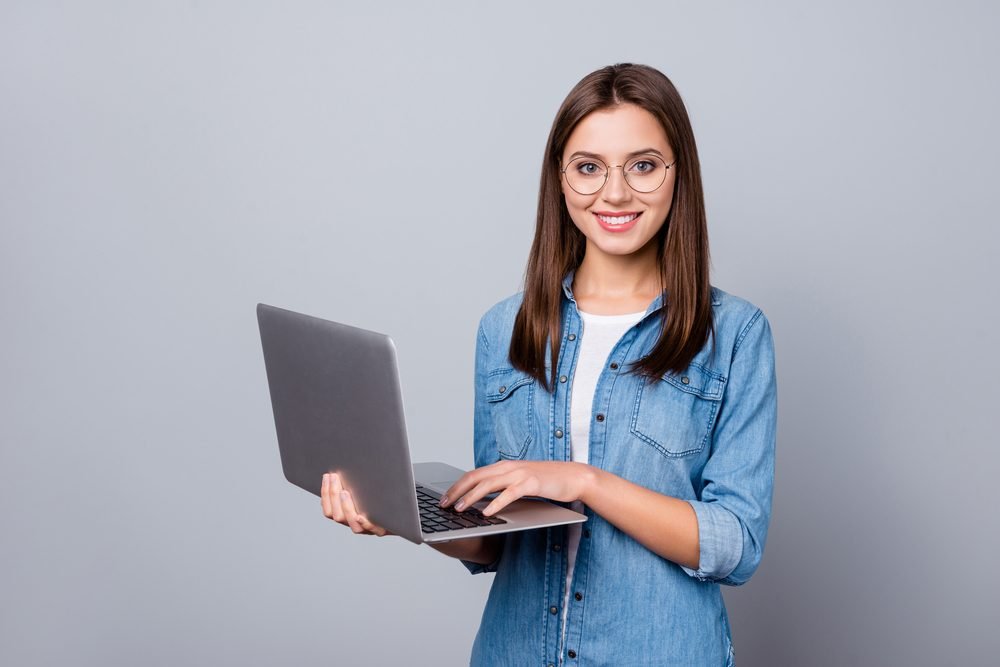 A student standing with a laptop on her palm, doing remote jobs for students