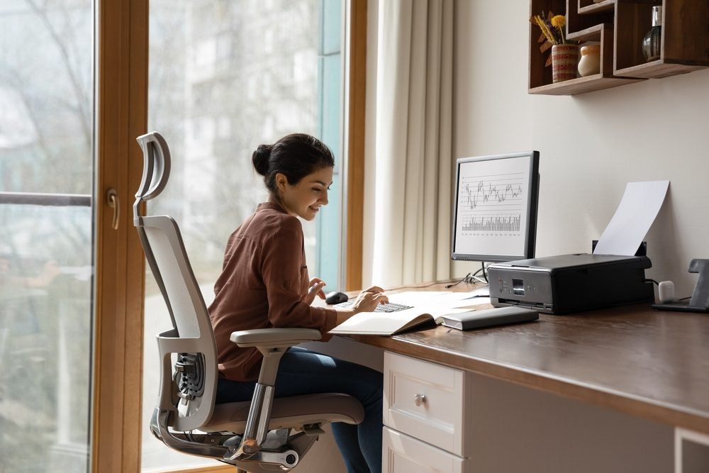 A lady sitting and working on her dedicated workspace after getting recruited for remote marketing jobs.