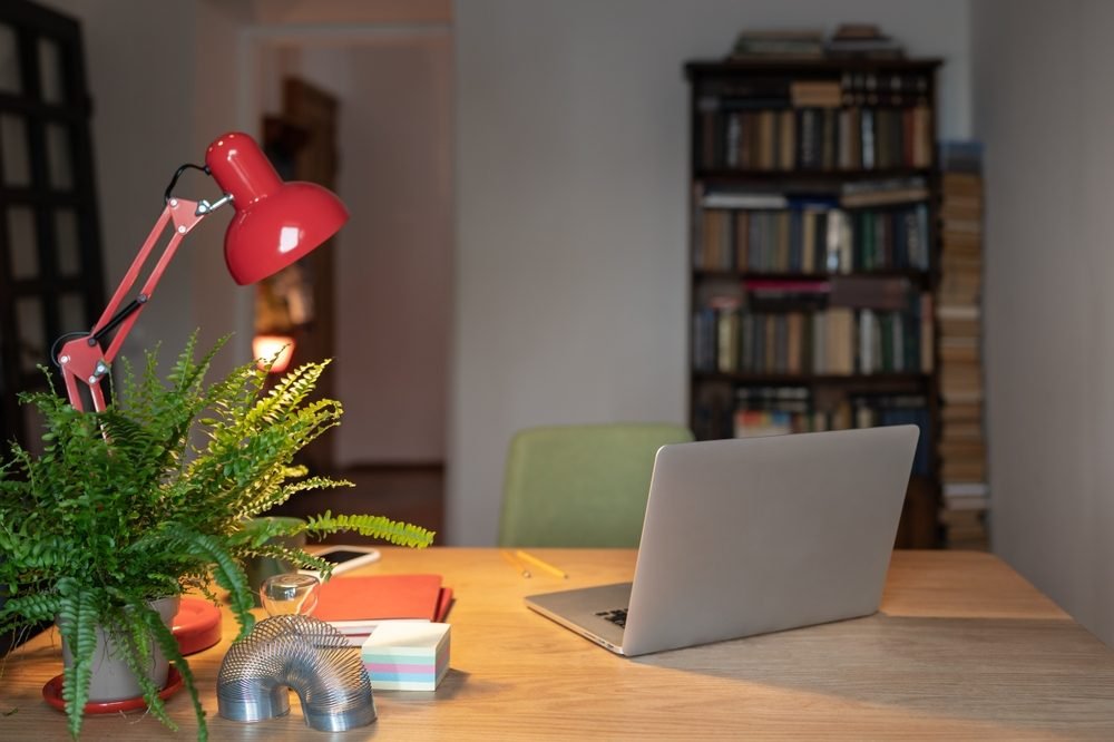 Remote Work Setup: Home office setup for remote working. Cozy comfortable workplace with laptop, desk lamp and office supplies nobody.